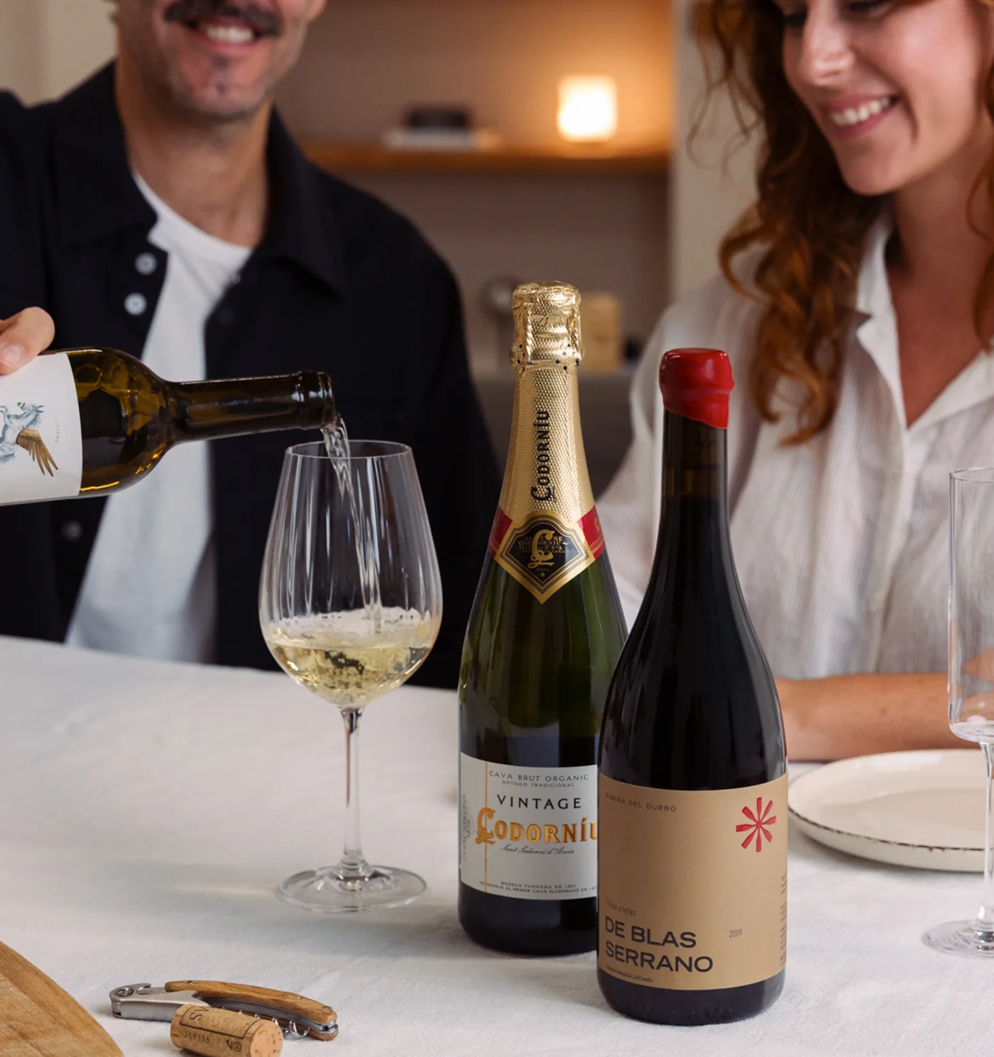 Coppia che brinda con vino bianco, cava e rosso a tavola