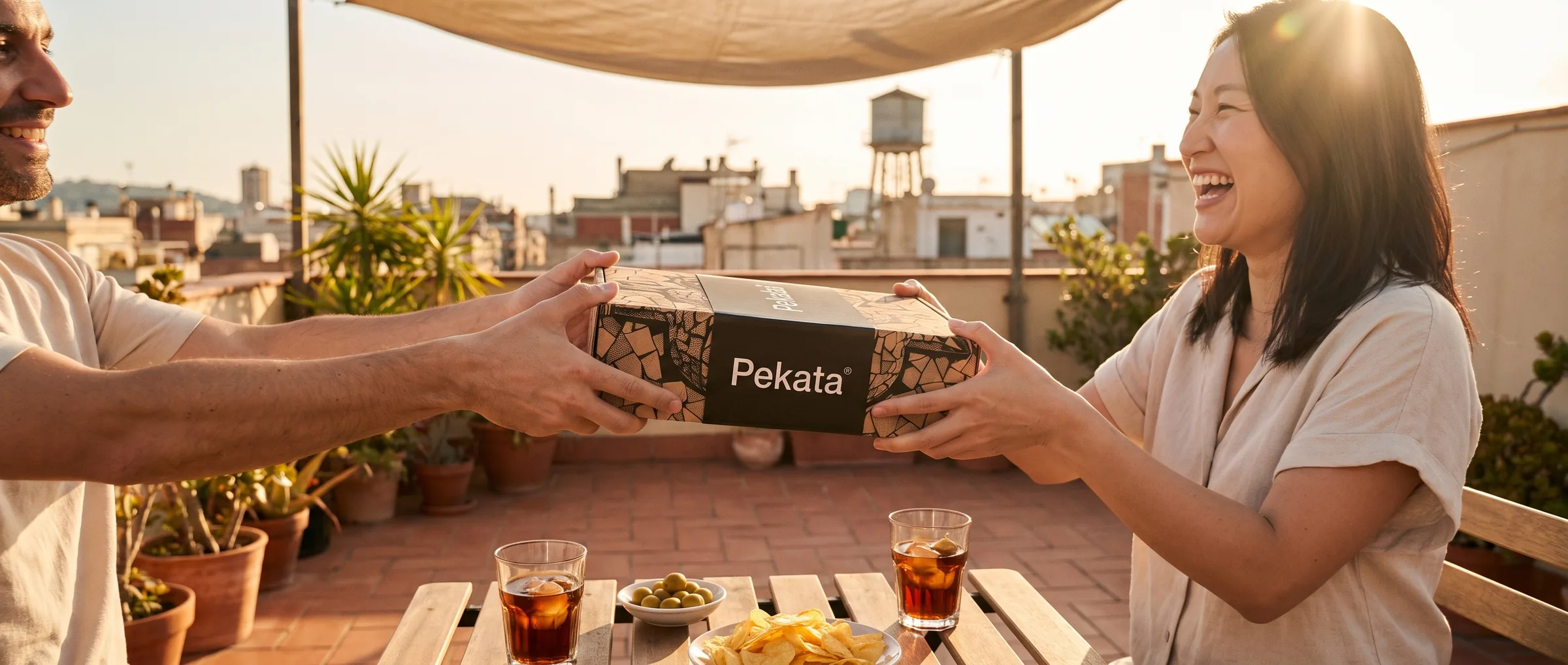 Due amici che si passano una scatola Pekata su una terrazza di Barcellona